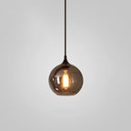 Round globe Clérachic smoked glass pendant, the bulb glowing amber through the mirrored tinted sphere.