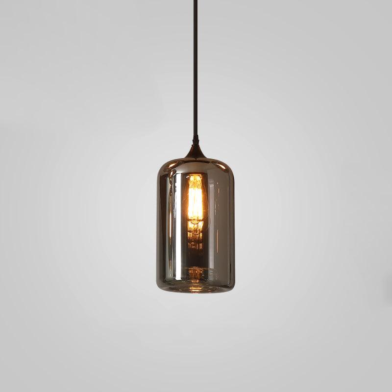 Tall cylinder Clérachic smoked glass pendant, its straight sides lit from within by a long filament bulb.