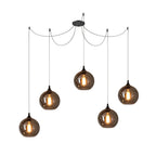 Five globe Clérachic smoked glass pendants on a five-cord spider canopy, hung at varied heights and all lit.