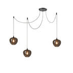 Three apple-bowl Clérachic smoked glass pendants on a spider canopy, hung at staggered heights and lit.