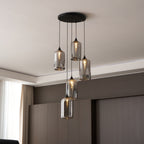 Round-canopy cluster of five Clérachic smoked glass cylinders, lit warm against dark timber panelling.