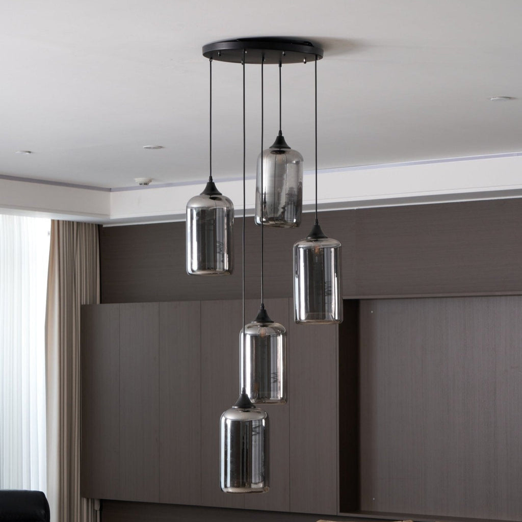 Five cylinder Clérachic smoked glass pendants hung under recessed downlights in a dark panelled room.