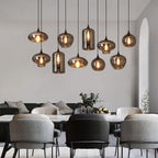 Ten Clérachic smoked glass pendants in mixed shapes over a marble dining table in a pale open-plan room.