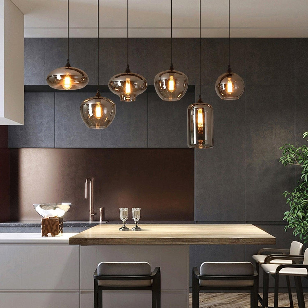 Kitchen island lit by Clérachic smoked glass pendants in five different shapes, hung in a staggered row.