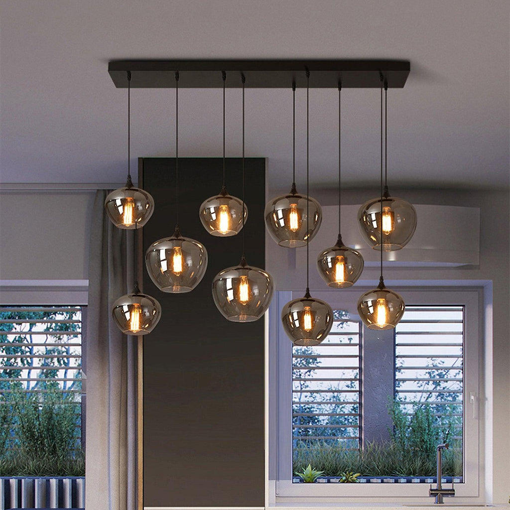 Ten apple-bowl Clérachic smoked glass pendants on a black rectangular canopy above a kitchen window.