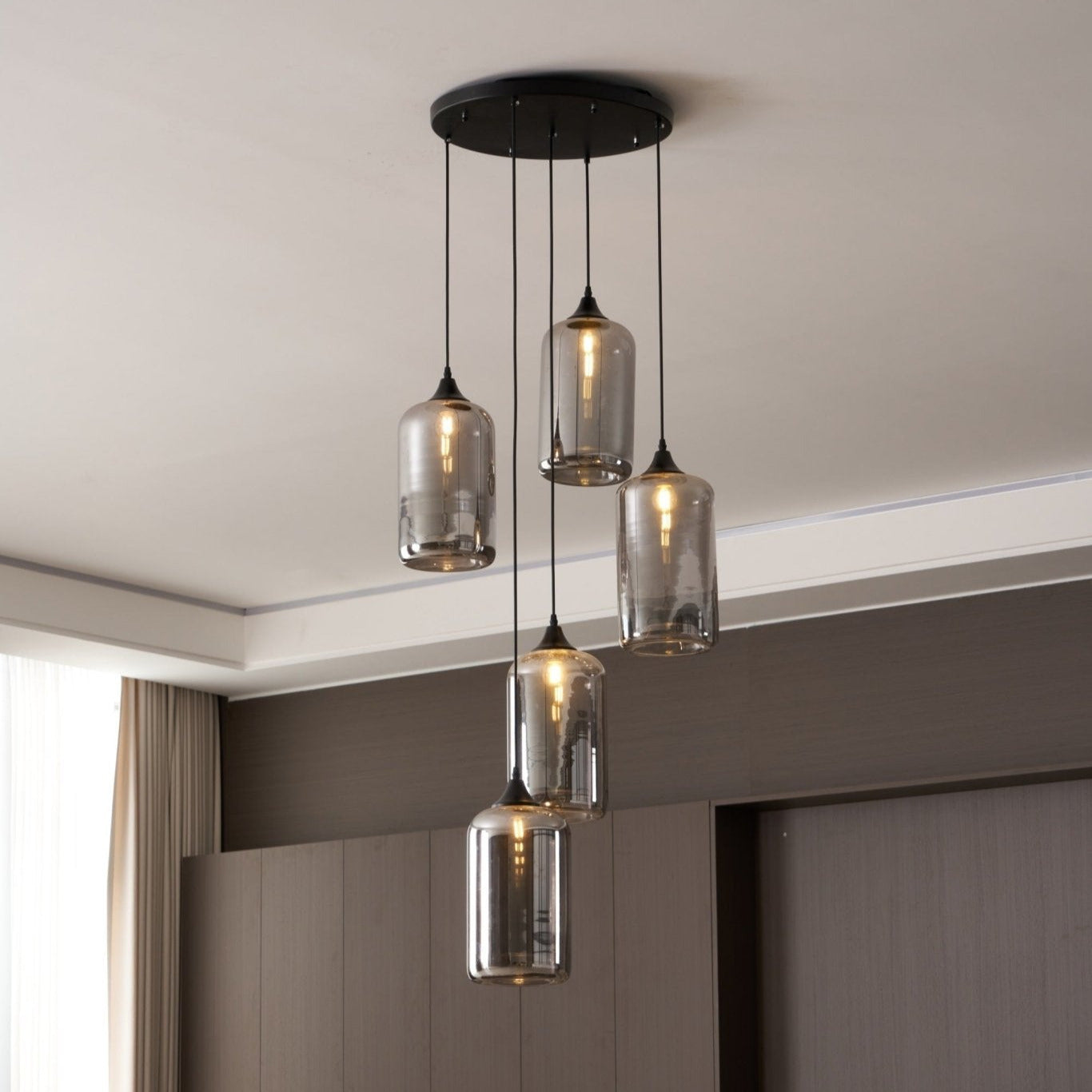 Round black canopy carrying five Clérachic smoked glass cylinders beside a curtained window.