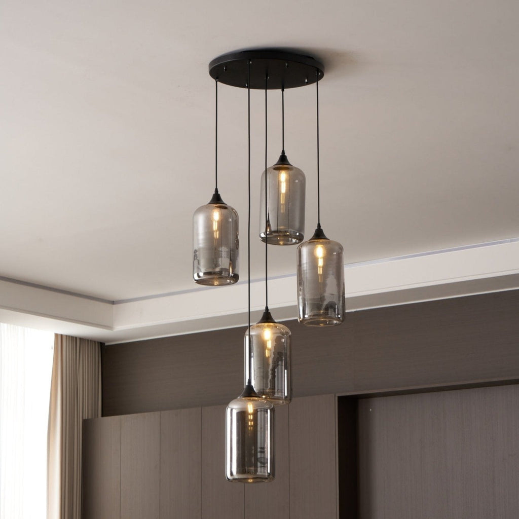 Close view of five lit Clérachic smoked glass cylinders, mirrored surfaces reflecting the room.