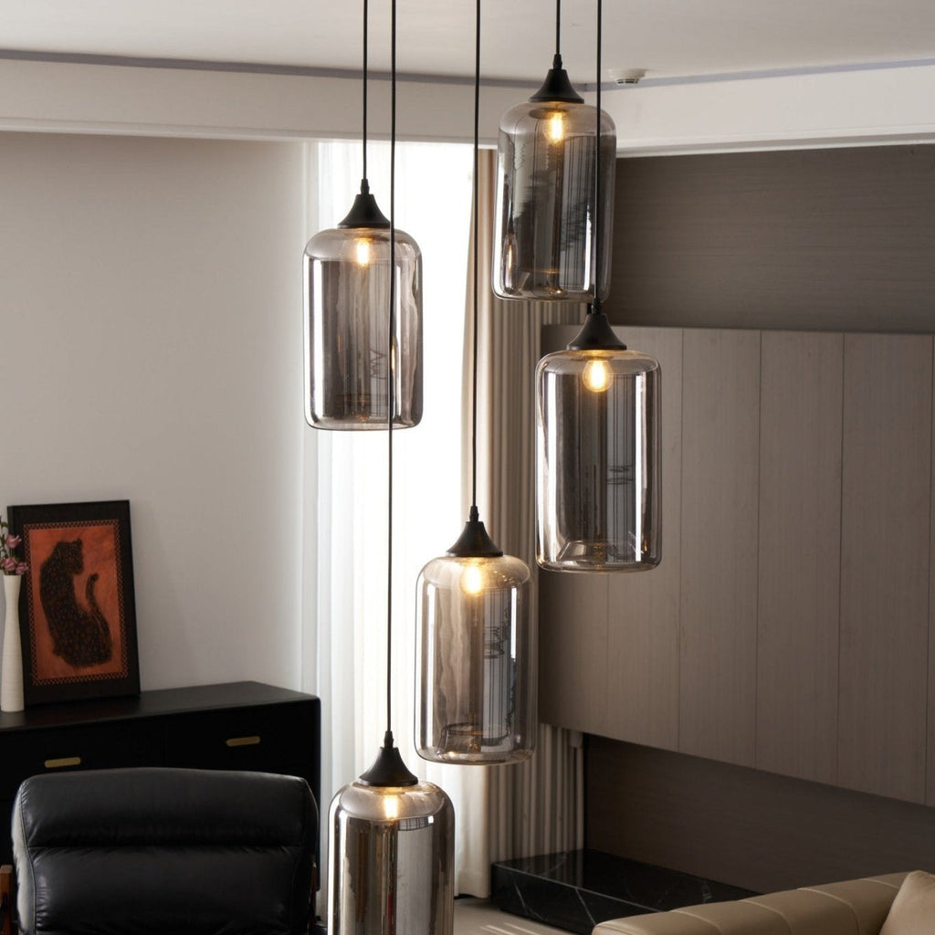 Five Clérachic smoked glass cylinder pendants by a bright window, with a framed print and cabinet behind.