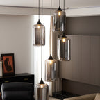 Five Clérachic smoked glass cylinder pendants by a bright window, with a framed print and cabinet behind.
