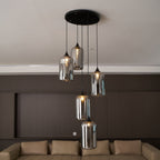 Five Clérachic smoked glass cylinders on a round canopy, hung above a long leather sofa.