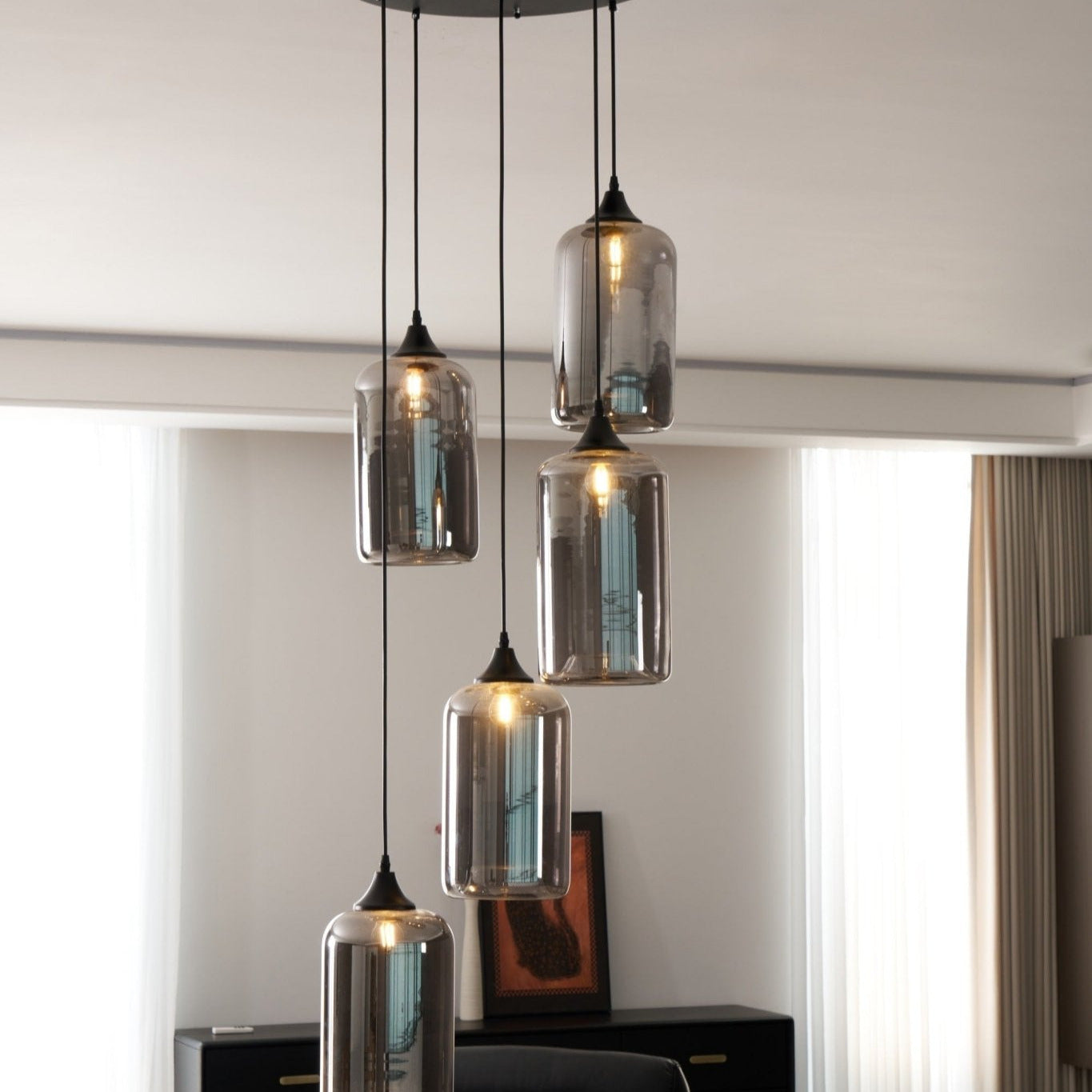 Clérachic smoked glass cylinder cluster in a bright sitting room, sheer curtains behind the lit shades.