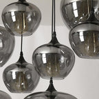 Close-up of clustered apple-bowl Clérachic smoked glass shades with their filament bulbs showing.