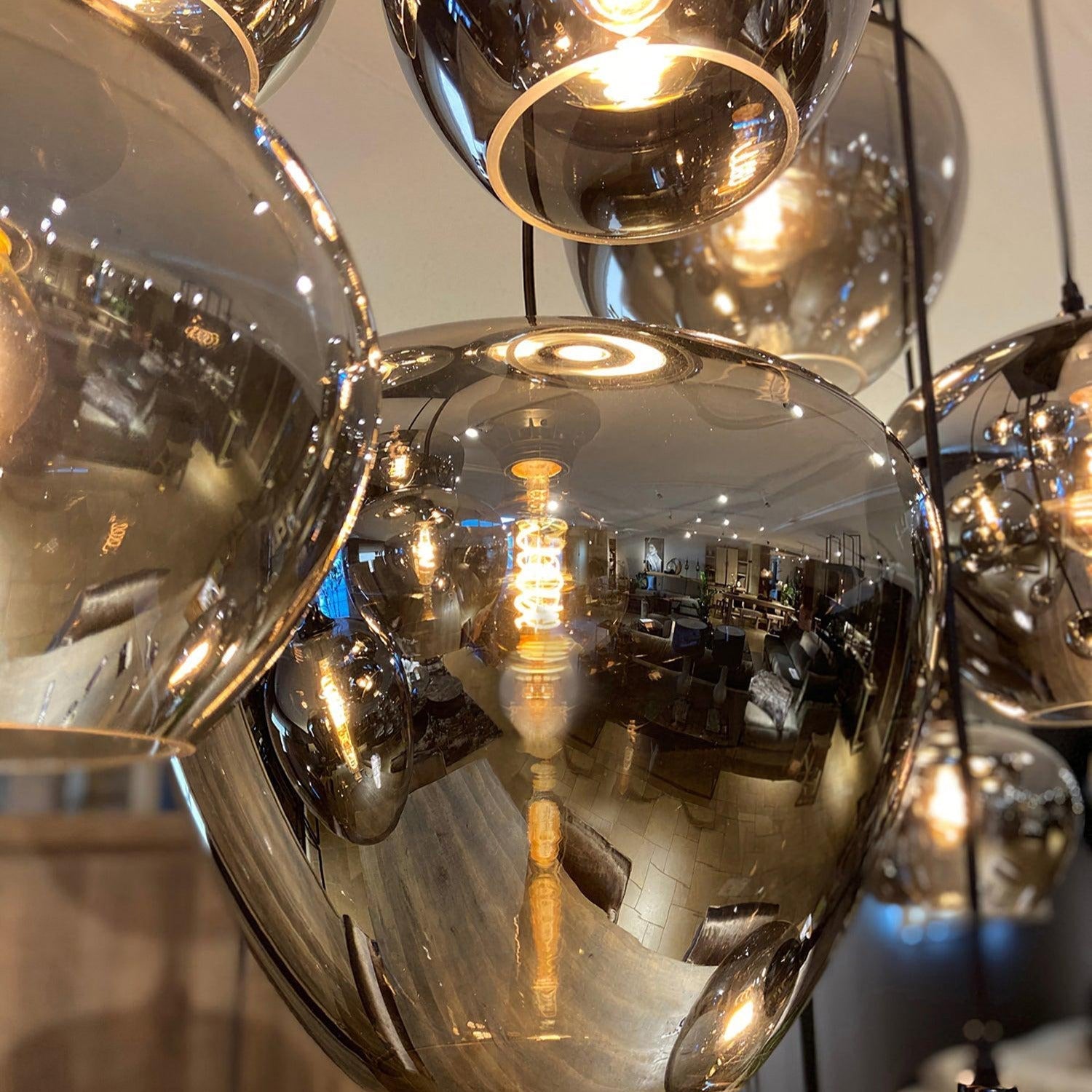 Clérachic smoked glass shades photographed close, the room reflected across their mirrored curves.