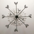 View from below of a black Clérachic chandelier on a ceiling rose, its arms ending in leaf shades wrapped in protective film.