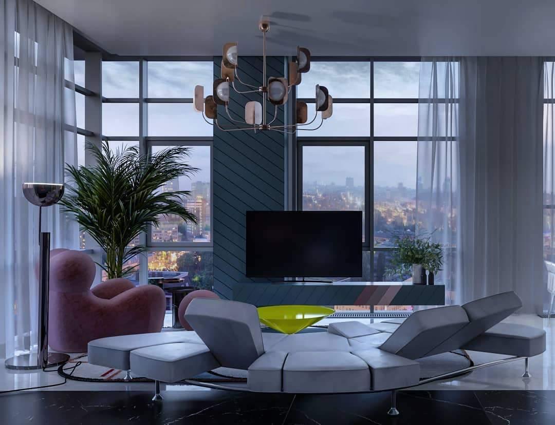 A Clérachic chandelier in a copper finish hangs above a curved grey sofa in a tower flat with floor-to-ceiling windows and a palm.