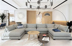 A black Clérachic chandelier hangs in a large open living room with a big grey corner sofa and an arched floor lamp.
