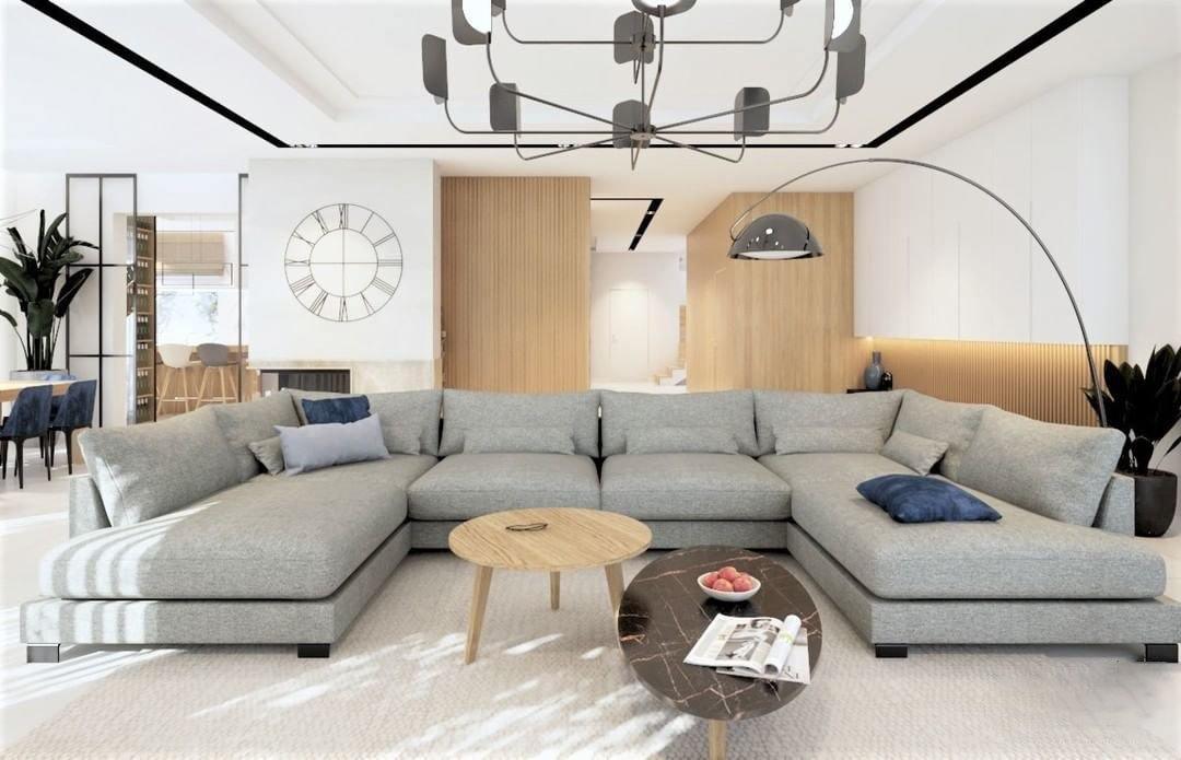 A black Clérachic chandelier hangs in a large open living room with a big grey corner sofa and an arched floor lamp.