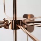 Close view of the copper hub on this Clérachic chandelier, with arms radiating from it and a soft leaf shade behind.