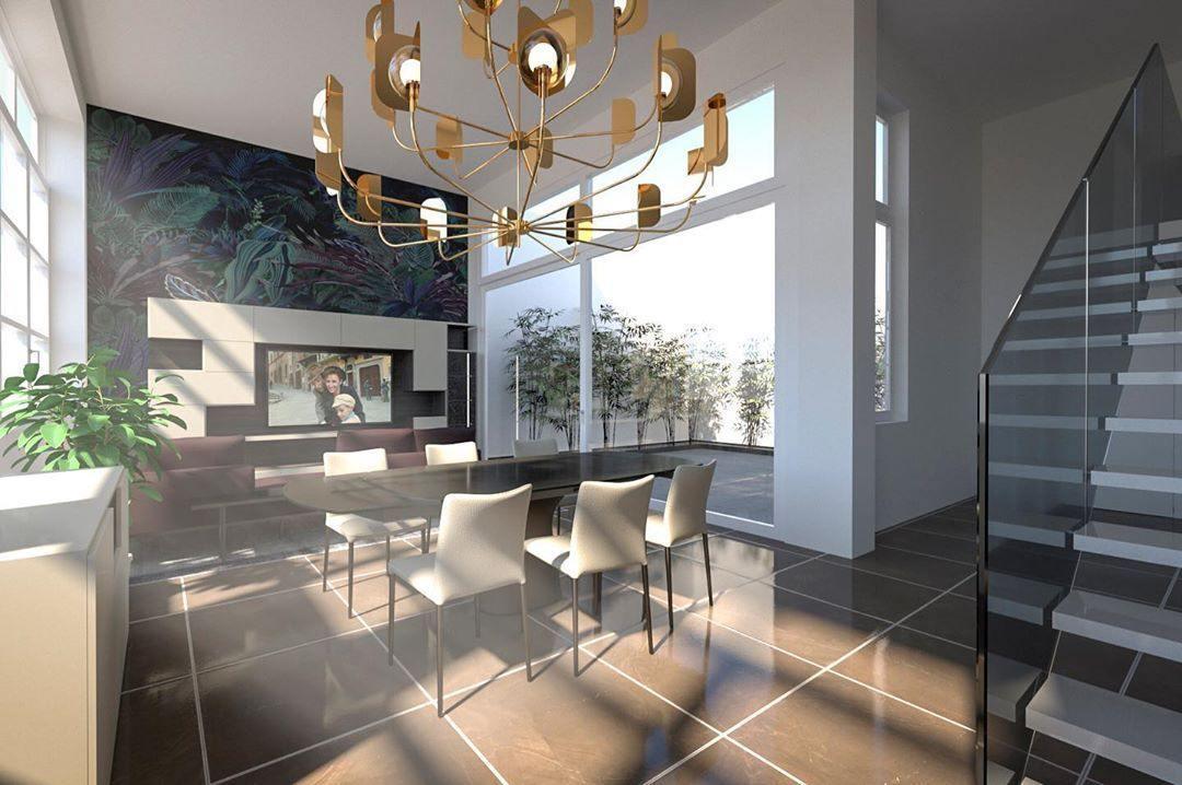 A brass-toned Clérachic chandelier in a visualisation of a stairwell room with large windows, a dining table and a dark tiled floor.