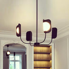 A black Clérachic chandelier on a rod, its leaf shades and a lit globe seen from below, with a plaster cornice and a glazed arch behind.