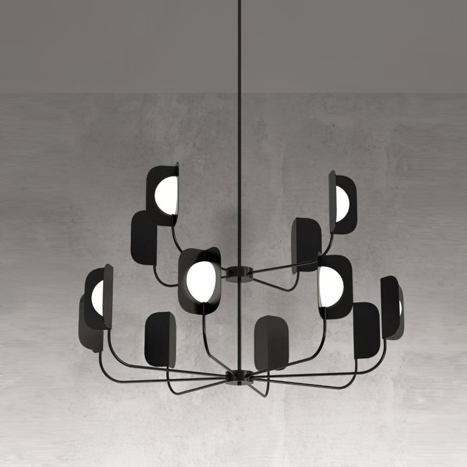 A black Clérachic chandelier in a concrete-look setting, two tiers of arms with leaf shades and glowing white globes.