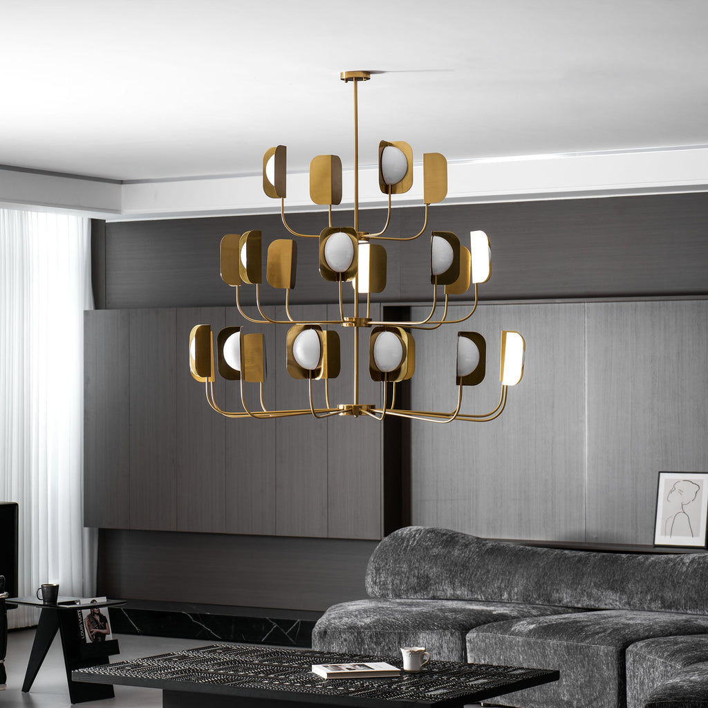 The same brass-toned Clérachic chandelier lit in the dark-panelled lounge, shown at a slightly lower angle with a curtain at left.