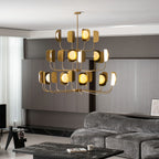 The brass-toned Clérachic chandelier lit in a dark-panelled lounge, with warm globes and leaf shades from the side.