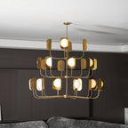 Three tiers of lit leaf shades on a brass-toned Clérachic chandelier, seen straight on above a sofa in a dark panelled room.