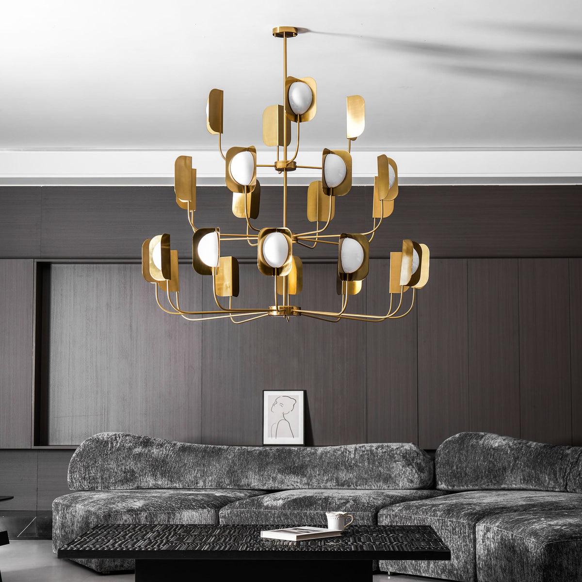 A brass-toned Clérachic chandelier seen from below in a dark-panelled lounge, with leaf shades and globes in rising tiers.