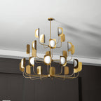 A brass-toned Clérachic chandelier with many leaf shades and unlit white globes, hung from a short rod beneath a white ceiling.