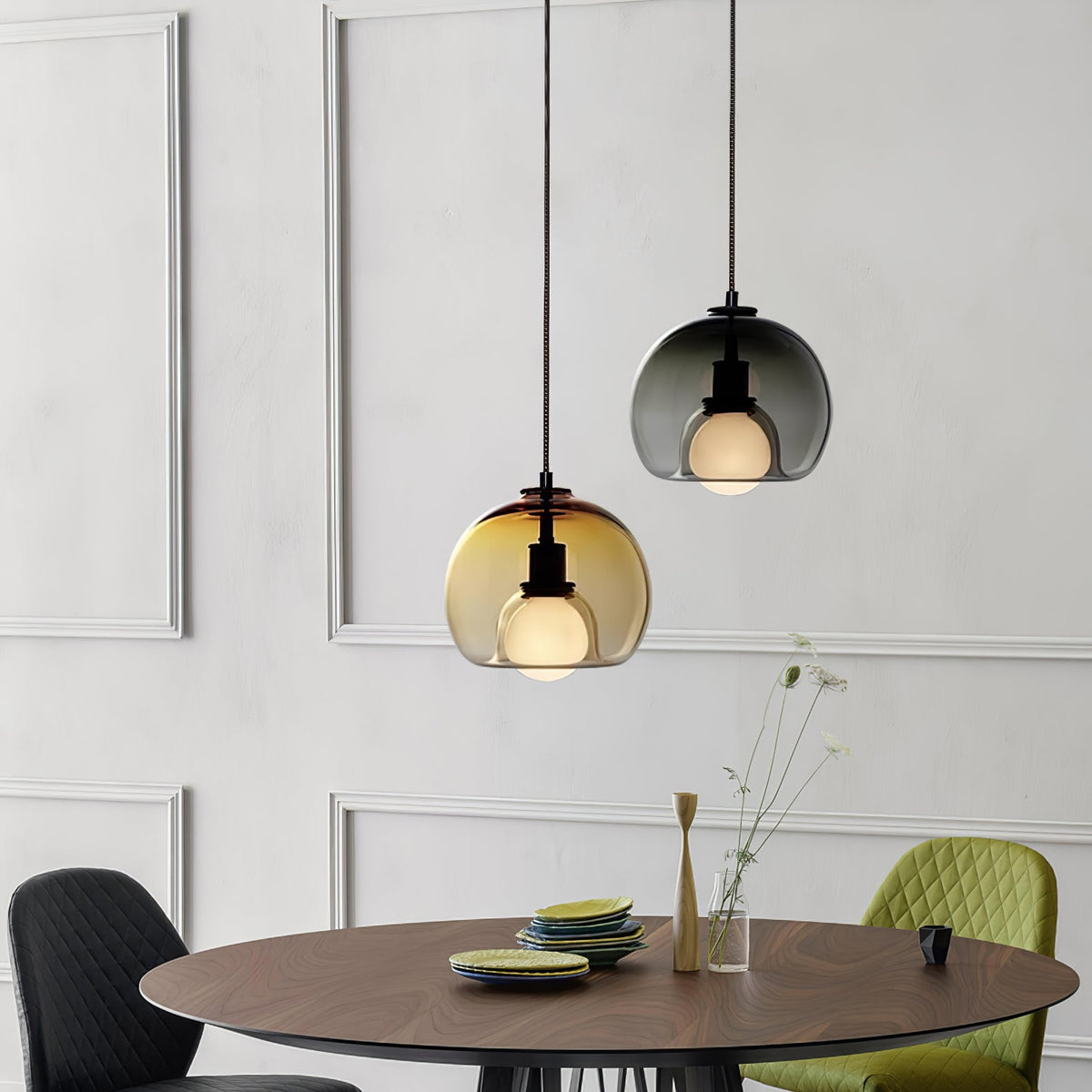 A cognac and a smoke Clérachic pendant hang over a round walnut table with a green chair in a panelled dining room.