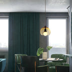 A cognac Clérachic pendant glows in a dark green dining corner with floor-length curtains and a small round table.