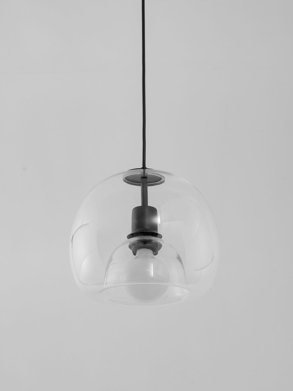 Angled view of the clear double-layer glass shade on this Clérachic pendant, with its black socket visible inside.
