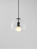 A clear glass Clérachic pendant hung from a black cord against a pale grey backdrop, with a lit frosted bulb.