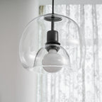 Close view of the inner glass dome and frosted bulb in this Clérachic pendant, in front of sheer curtains.