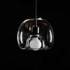 Close view of the clear glass shade, frosted bulb and black socket on this unlit Clérachic pendant in a dark room.