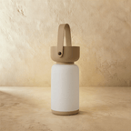 Clérachic cordless cylinder lamp switched off, a white frosted body with a taupe-brown handle and base on plaster.