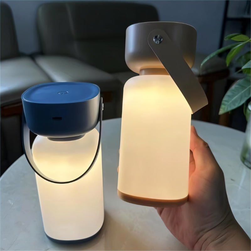 Clérachic cordless cylinder lamps glowing warm on a marble table, one with a blue top and one held in a hand.