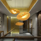 Three Clérachic bamboo pendants lit at staggered heights above a gold-screened stairwell.