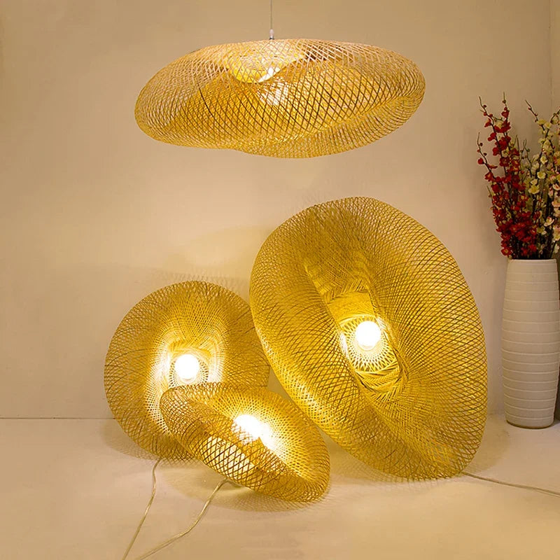 Clérachic bamboo pendants lit in a group, one hanging and two resting beside a tall vase.