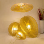 Clérachic bamboo pendants lit in a group, one hanging and two resting beside a tall vase.