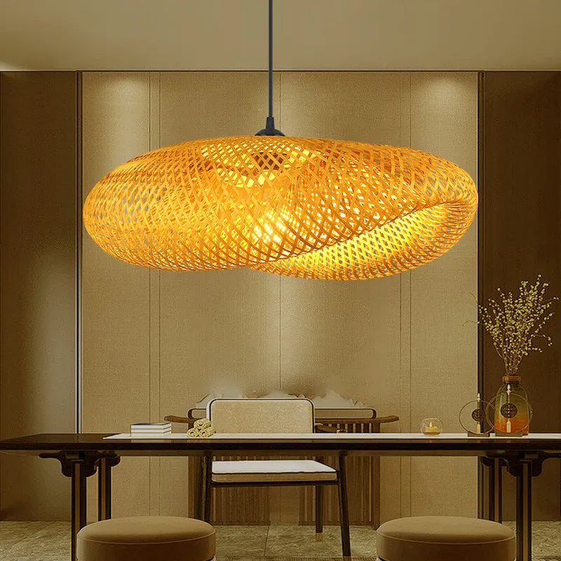 The Clérachic bamboo pendant lit above a dark timber dining table against a linen wall.