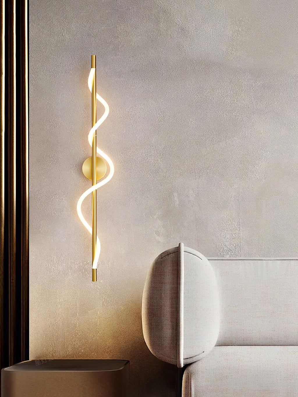 Beside a sofa, this brass Clérachic wall light has a glowing spiral band on a plaster wall, with a dark column at the left.