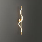 On a dark grey wall, a brass Clérachic wall light shows its glowing silicone spiral.