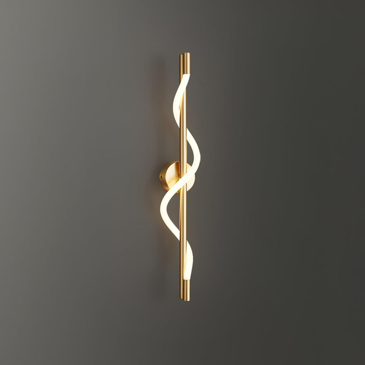 On a dark grey wall, a brass Clérachic wall light shows its glowing silicone spiral.