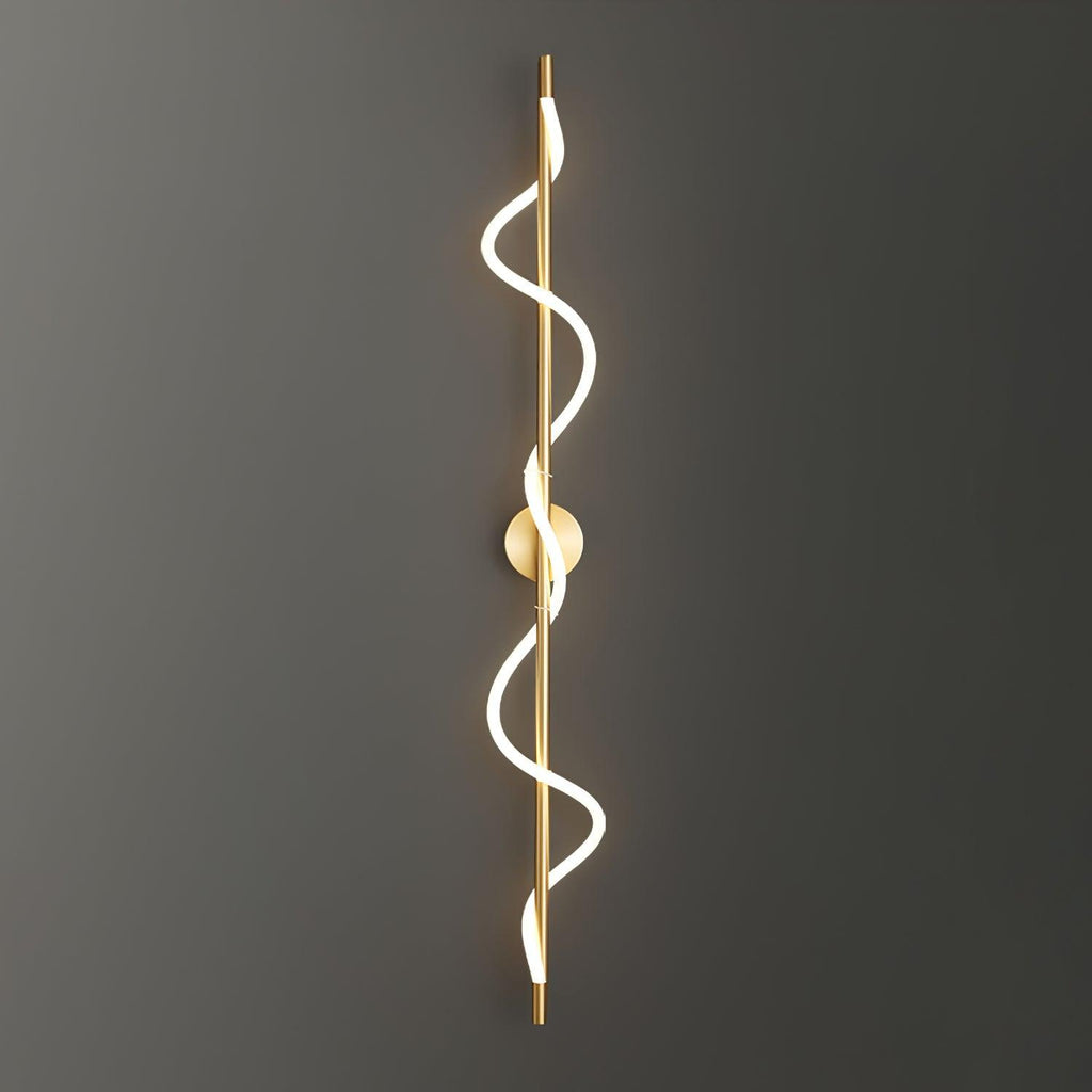 A long brass Clérachic wall light with a two-turn lit spiral, mounted on a dark grey wall that fades to black.