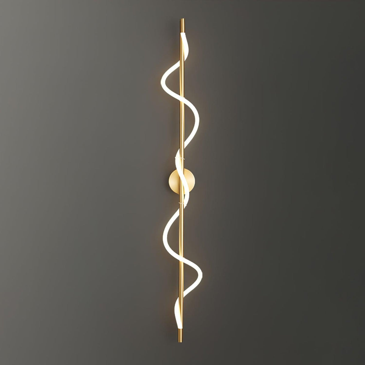 A long brass Clérachic wall light with a two-turn lit spiral, mounted on a dark grey wall that fades to black.