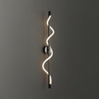 Against a dark grey wall, the bright two-turn spiral band of a black Clérachic wall light glows.