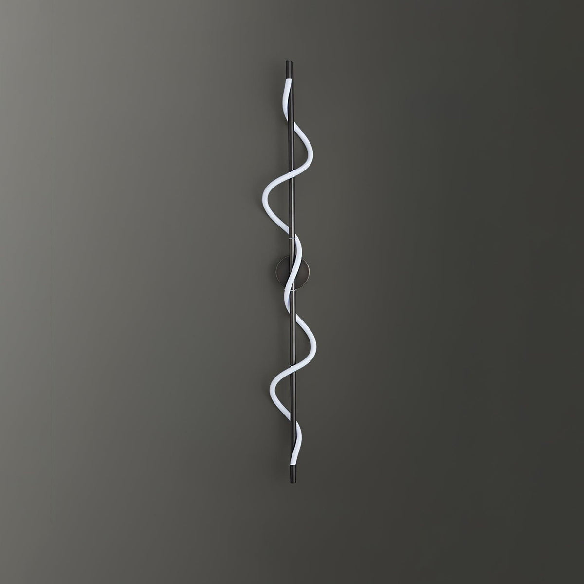 A black Clérachic wall light with a cool white spiral band on a dark grey wall, with the round backplate behind the rod.