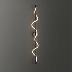 Glowing on a dark grey wall, a black Clérachic wall light with a two-turn spiral band and a round backplate.